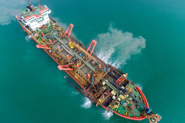 Aerial drone shot of a TSHD dredger operating at sea, removing sediment from the seabed for harbor...