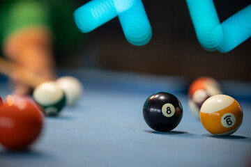 Black 8-Ball in Foreground on Pool Table with Vibrant Blurred Lights in Background, copy space photo