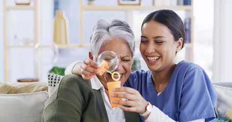 Nurse, old woman and blowing bubbles with laugh, medical support and happy in retirement home. Soap...
