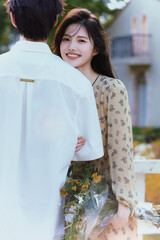 Young couple enjoying a beautiful outdoor moment with flowers in a tranquil setting.