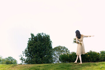 Female in Floral Dress Standing in Serene Landscape.
