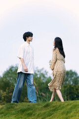 A young couple standing on a grassy hill, engaged in conversation.