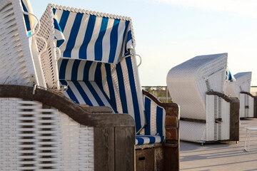 Empty canopied wicker-style beach chairs await vacationers