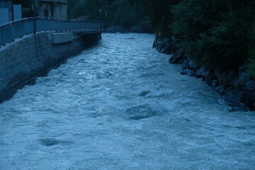 Mountain river flowing through Swiss village at dusk