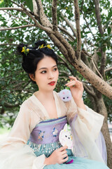 A young woman in traditional clothing poses gracefully under a tree Chinese word means cute.