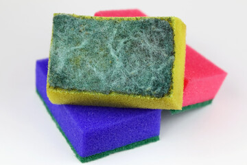 Two new sponges with one used and dirty sponge on top