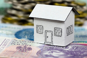 A model of a small house made of paper has been placed on the Polish Zloty banknotes