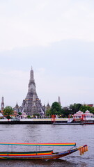 Boat trip on the Chao Phraya River with Wat Arun in the background in Bangkok, Thailand.