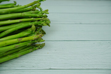 Bunch of fresh green asparagus stems on wooden background