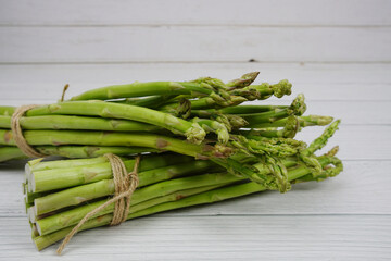 Bunch of fresh green asparagus stems on wooden background