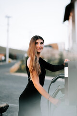Young woman fueling her vehicle at an elegant gas station in a rural area during the late afternoon