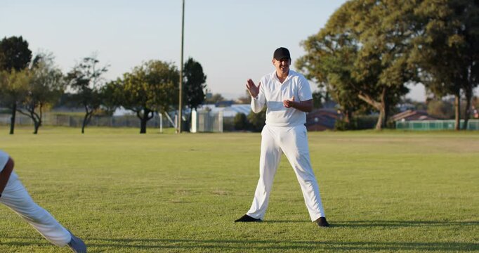 Practicing fielding after underhand toss by Diverse male team on grass with cricket ball and stump