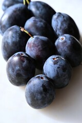 Close-up of fresh plums showing a variety of rich blue and purple tones. The natural color gradient highlights the fruit’s ripeness and freshness. Ideal for healthy food and organic produce themes.