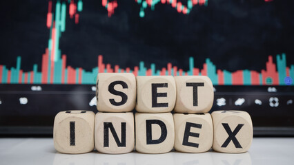 Wooden blocks spelling SET INDEX are placed in front of digital stock market chart displaying...