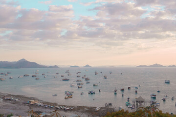 Scenery of sunset time at Labuan Bajo harbor with boat sailing in the ocean.