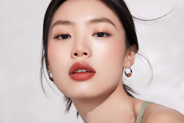 Close-up of a young woman with natural makeup and jewelry.