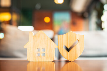 Wooden house and shield with check mark represent home protection, property insurance, and housing...