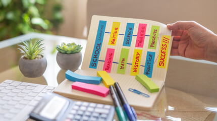 Student is organizing their school projects, using colorful sticky notes on a notebook, focusing on...