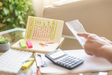 Parent is calculating school supply expenses using a calculator and a shopping list, preparing for back to school season and ensuring they have enough budget