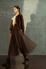 Fashion model in elegant outfit walking against a textured background.