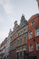  Low-angle shot of a row of colorful, historic buildings with ornate facades and unique gables. The image highlights the detailed architecture and vibrant charm of a European street.