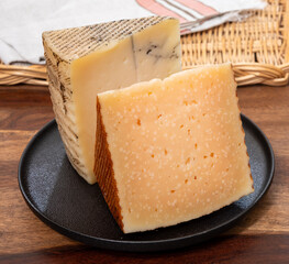 Two pieces of Spanish hard cheese, cow and sheep curado, manchego, goat cheese with added black...