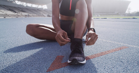 Shoes, tying laces and hands on stadium, prepare for running or sports for workout on race track....