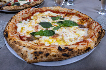 Eating of fresh baked Naples pizza dish in italian pizzeria restaurant, close up