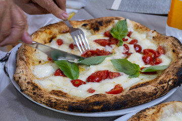 Eating of fresh baked Naples pizza dish in italian pizzeria restaurant, close up