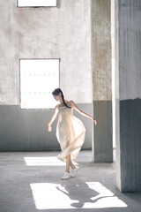 A young woman dancing gracefully in a spacious industrial setting.