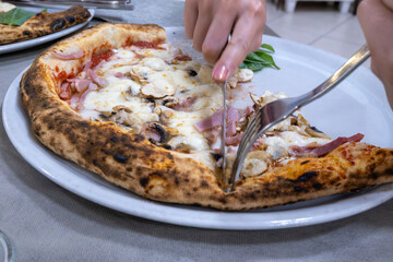 Eating of fresh baked Naples pizza dish in italian pizzeria restaurant, close up