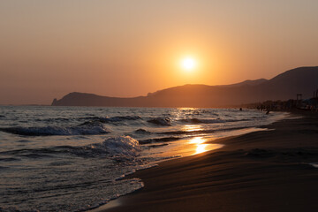 Silhouettes of swimming people on sunset in sun lights, sandy beach near Sperlonga, Lazio, italy,...
