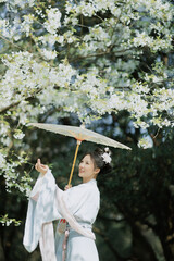 Woman with an umbrella among blooming flowers in a serene outdoor setting.