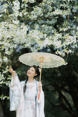 A woman in traditional attire enjoying the beauty of cherry blossoms under a parasol.