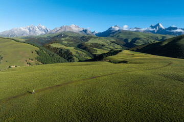 Obraz premium Aerial view of woman riding mountain bike on flowering grassland mountain trail