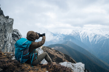 Successful woman hiker use mobilephone at mountain top in tibet