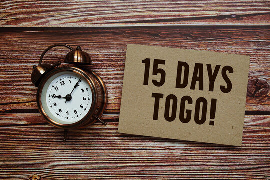 15 Days To Go! text with alarm clock on wooden background