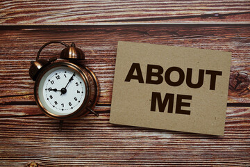About Me text with alarm clock on wooden background
