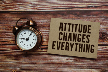 Attitude Changes Everything text with alarm clock on wooden background