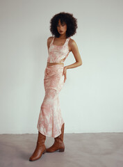 Fashionable young woman in stylish outfit with curly hair posing confidently.
