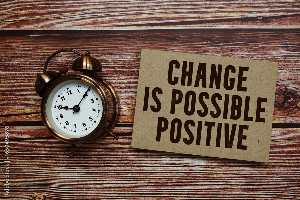 Poster change is possible positive text with alarm clock on wooden background
