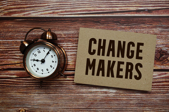 Change Makers text with alarm clock on wooden background