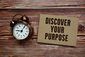 Discover Your Purpose text with alarm clock on wooden background