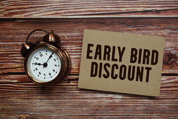 Early Bird Discount text with alarm clock on wooden background