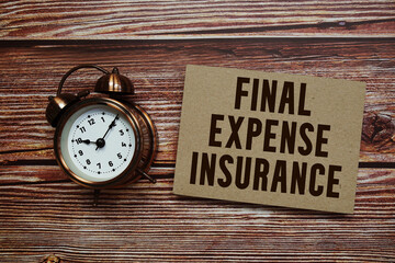 Final Expense Insurance text with alarm clock on wooden background