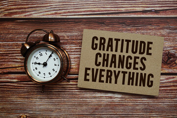 Gratitude Changes Everything text with alarm clock on wooden background