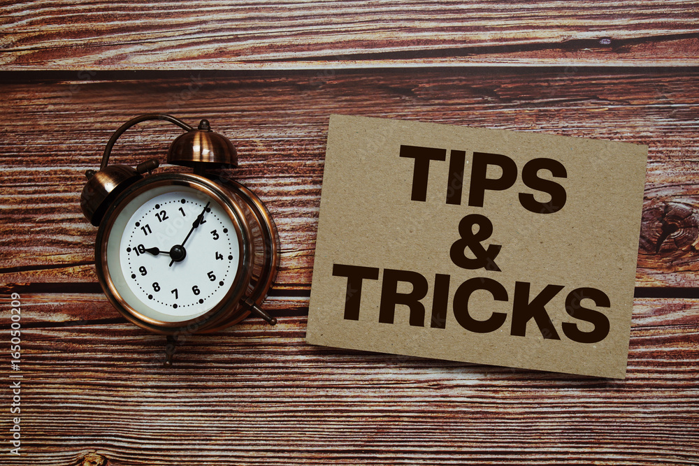Poster tips and tricks text with alarm clock on wooden background