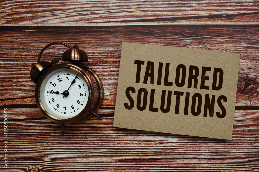 Poster tailored solutions text with alarm clock on wooden background