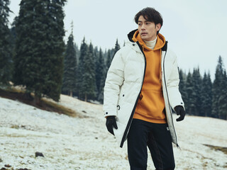 Young man in winter clothing standing in a snowy landscape.