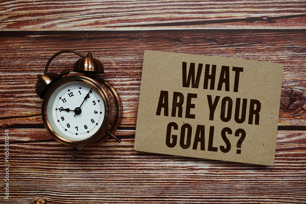 Poster what are your goals? text with alarm clock on wooden background